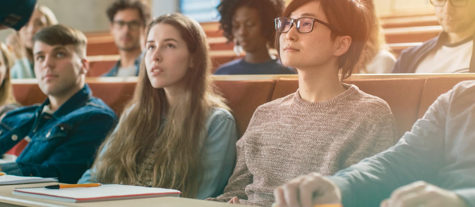 A diverse group of university students look up at a lecturer